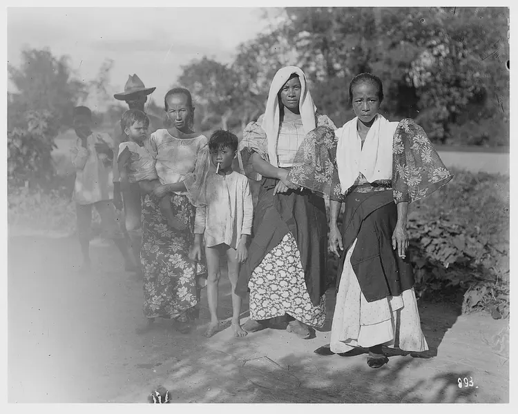 Members of a Filipino family including an older woman with a toddler, a small boy with a cigarette in his mouth, and two women.