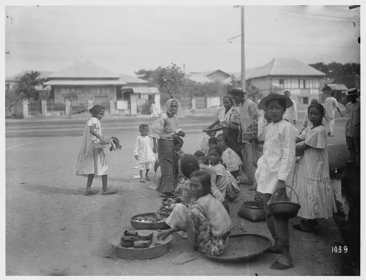 Street vendors, mostly children, sit on the roadside and offer their wares from round baskets.